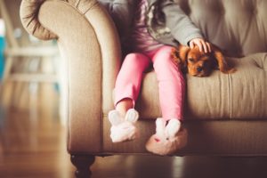 child sitting on sofa with dog